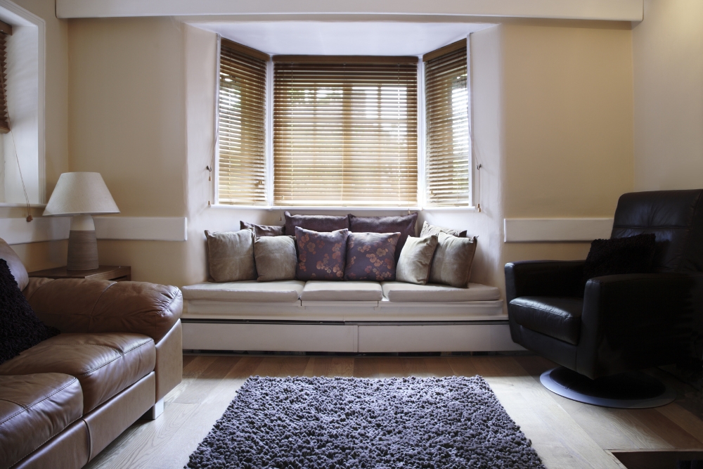 Cosy living room with wooden motorised blinds, offering seamless light adjustment and privacy while complementing the warm, inviting decor.